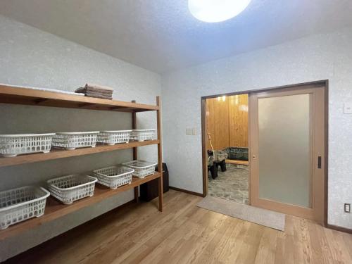 an empty room with baskets on shelves and a door at AKANE Hostel あかね天然温泉旅館 in Yuzawa