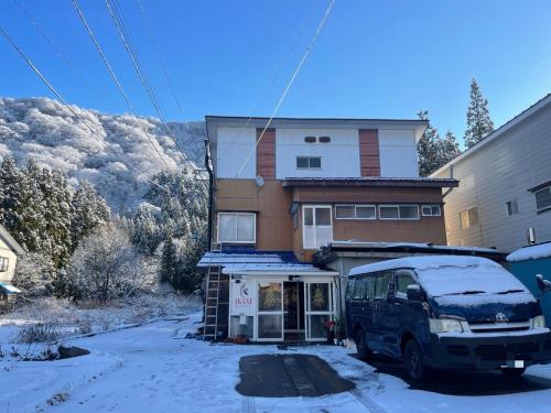a van parked in front of a house in the snow at AKANE Hostel あかね天然温泉旅館 in Yuzawa