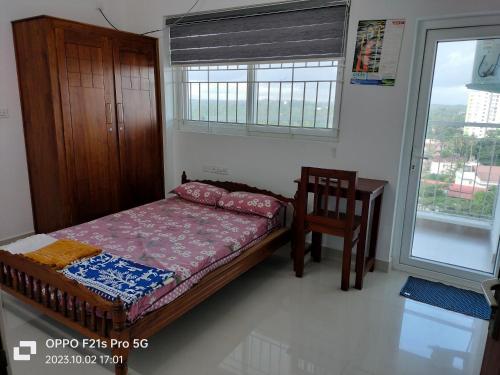 - une chambre avec un lit, une chaise et une fenêtre dans l'établissement Ajith's Inn, à Kottayam