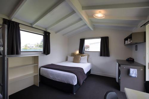 a small room with a bed and two windows at Tasman Holiday Parks - Papamoa Beach in Papamoa