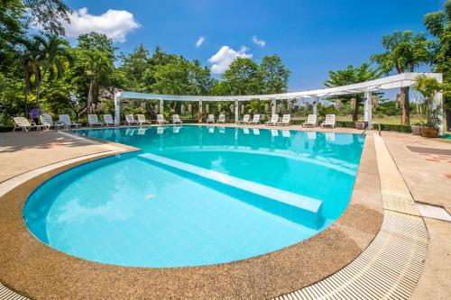 a swimming pool with chairs and a gazebo at The Legacy River Kwai Resort in Kanchanaburi City