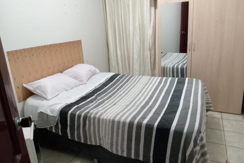 1 dormitorio con 1 cama con manta a rayas y espejo en Comodidad en tu viaje, en Chiclayo