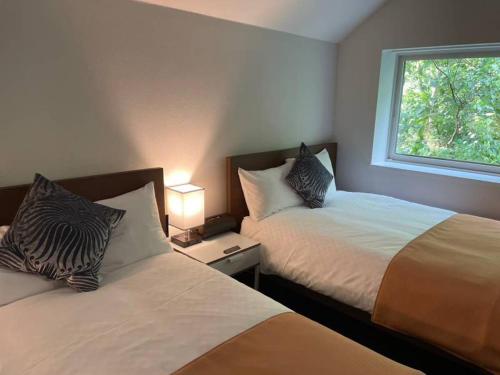 a bedroom with two beds and a window at ユニテ蔵王ジョーニダ リゾート in Yamagata