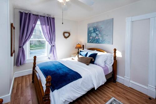 HartfordにあるVintage downtown flat near Holy Hill, Golf &Skiのベッドルーム1室(紫色のカーテンが付いた大型ベッド1台付)