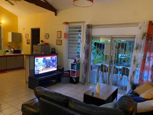 a living room with a couch and a television at Belle maison équipé avec piscine in Mamoudzou