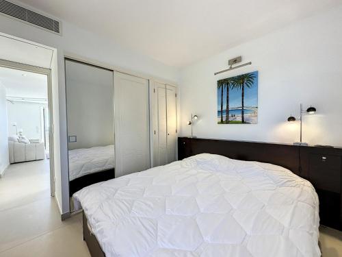 een witte slaapkamer met een bed en een spiegel bij Appartement Cannes, 3 pièces, 6 personnes - FR-1-470-66 in Cannes