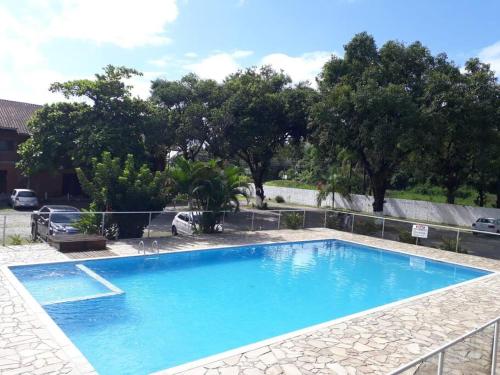 a large blue swimming pool with trees in the background at Apto Chocolate Maranduba Ubatuba in Ubatuba