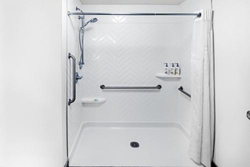 a shower in a bathroom with a white tub at Holiday Inn Hotel & Suites Tulsa South, an IHG Hotel in Tulsa