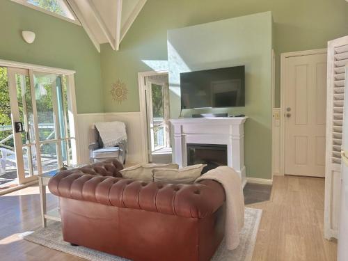 Apollo Bay的住宿－Apple Tree Cottage，客厅配有棕色真皮沙发和壁炉