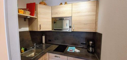 eine Küche mit einer Spüle und einer Mikrowelle in der Unterkunft FeWo Nordsee Whg. 11 in Sankt Peter-Ording