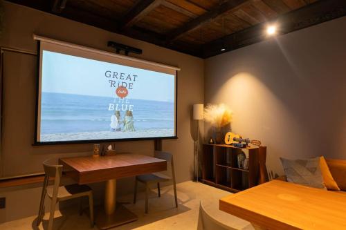 una pantalla de proyección en una pared de la sala de estar en NEW OPEN ！1日1組限定、海すぐの一軒家を完全貸切別荘！島の自然を五感で味わえる体験型ホテル en Shikanoshima