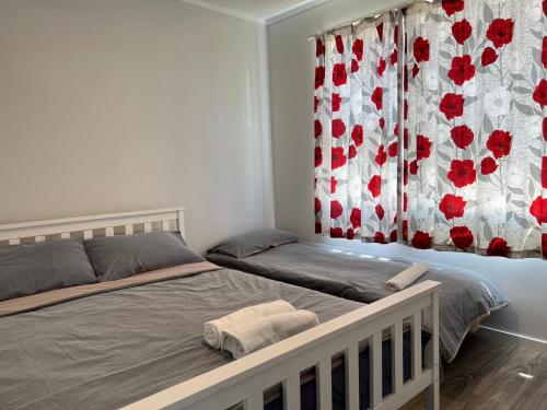 ein Schlafzimmer mit einem Bett und einem Vorhang mit roten Blumen in der Unterkunft Cozy 2 bedrooms Studio 6A Chapman Place, no kitchen in Rotorua