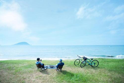 two people sitting in chairs looking at the ocean at NEW OPEN ！1日1組限定、海すぐの一軒家を完全貸切別荘！島の自然を五感で味わえる体験型ホテル in Shikashima