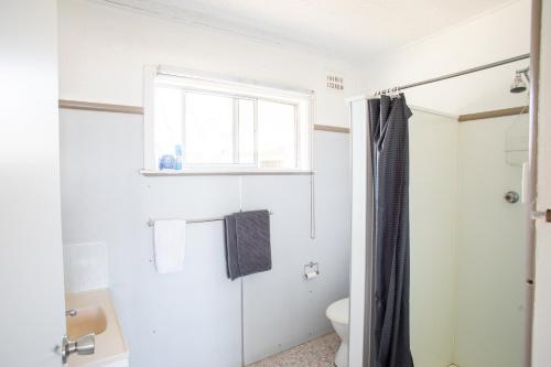 een witte badkamer met een toilet en een raam bij Harwood Hotel 