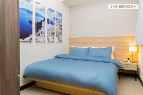 台北2B1bLK, Stylish & Comfortable, 5 Min to Ximen MRT • 2房1衛 客廳廚房 時尚舒適 5分到西門站的卧室里有一张蓝色的床，还有一张桌子和两幅画