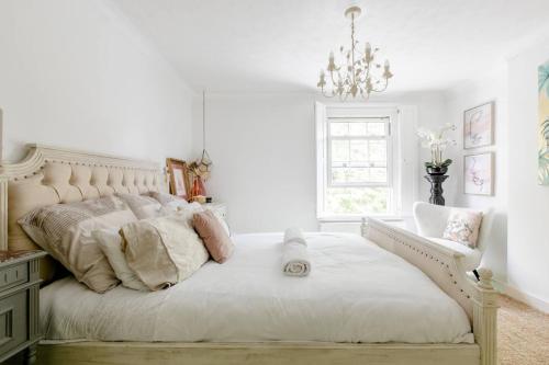 a white bedroom with a large bed with a chandelier at Quaint 2-Bed Cottage in the heart of Ashford in Ashford