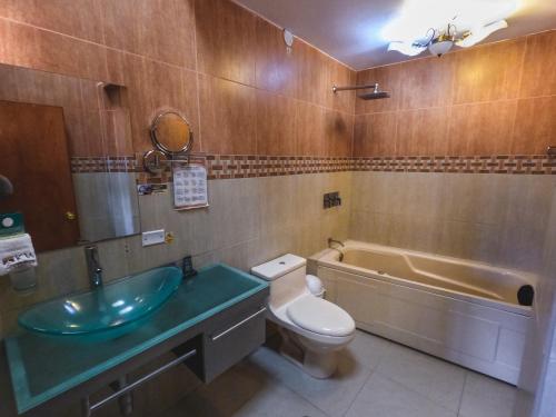 a bathroom with a sink and a toilet and a tub at Gran Kunturwasi Hotel Senior in Cajamarca
