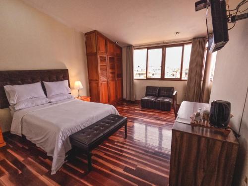 a bedroom with a bed and a chair in it at Gran Kunturwasi Hotel Senior in Cajamarca