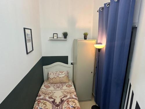 a small bedroom with a bed and a blue curtain at Private Partition Room Near Mashreq Metro in Dubai