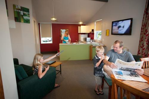 a man and two children sitting at a table in a room at Kennedy Park Resort Napier in Napier