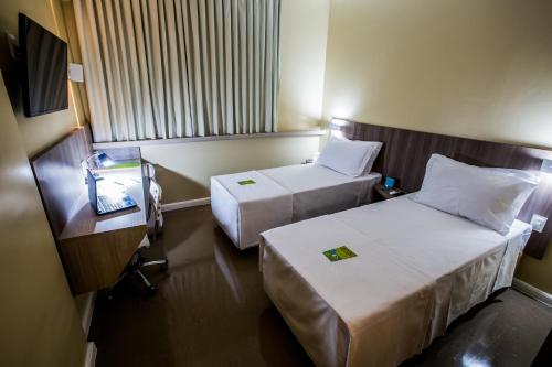 a hotel room with two beds and a table at Slim Cuiabá Aeroporto in Cuiabá