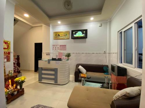 ein Wohnzimmer mit einem Sofa und einem TV an der Wand in der Unterkunft Phước Hưng 1 Hotel in Vĩnh Long