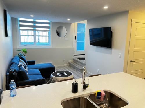 uma cozinha e sala de estar com um lavatório e um sofá em The Waterfront cozy 1 bd suite in Rockland Park, Tuscany NW em Calgary