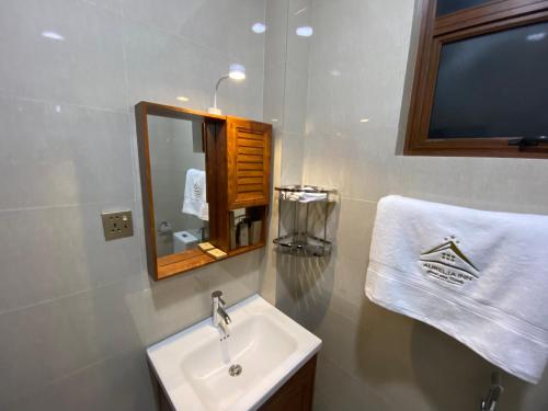a bathroom with a sink and a mirror and a towel at Aurelia inn in Kandy