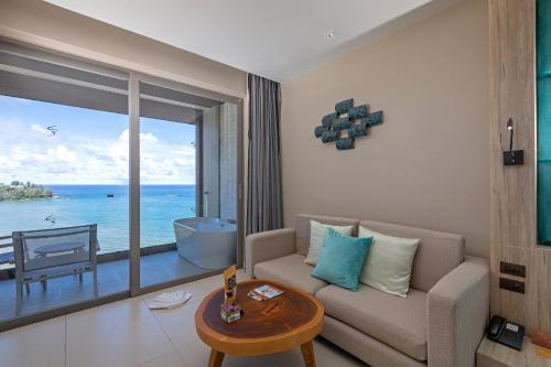 a living room with a couch and a view of the ocean at Cape Sienna Phuket Gourmet Hotel & Villas - SHA Extra Plus in Kamala Beach