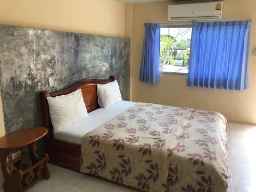 a bedroom with a bed and a window with blue curtains at Ratchaphruek Resort in Lop Buri