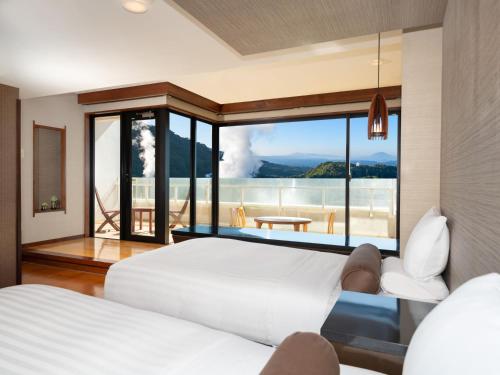 a bedroom with two beds and a view of the ocean at Kirishima Kokusai Hotel in Kirishima