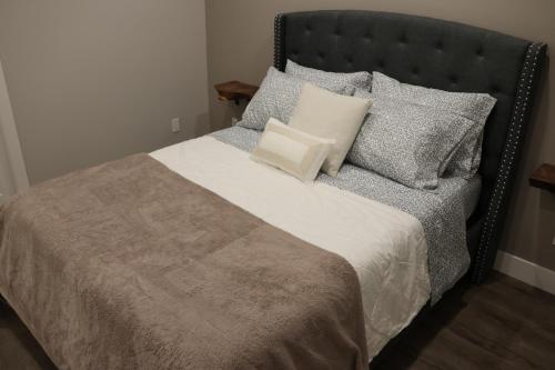 a bedroom with a bed with a black headboard and pillows at Golden Ears Nature's Delight in Maple Ridge District Municipality