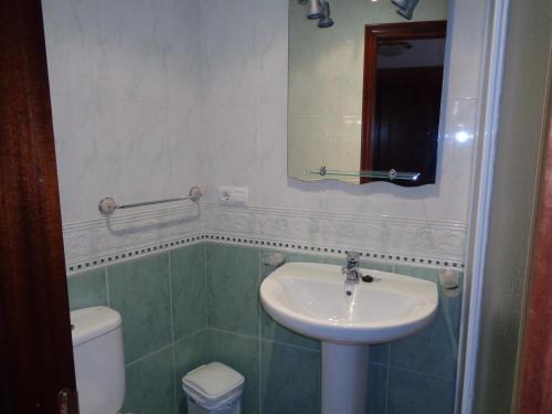 a bathroom with a sink and a toilet and a mirror at Apartamentos San Pelayo in Cangas de On&iacute;s
