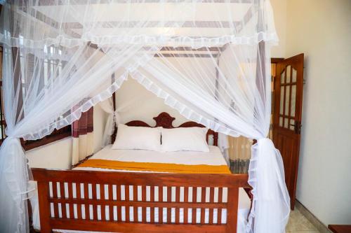 1 dormitorio con cama con dosel y cortinas blancas en Vision Home, en Ambalangoda