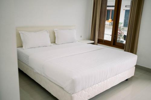 a white bed with white pillows in a bedroom at Morika Inn in Waikabubak