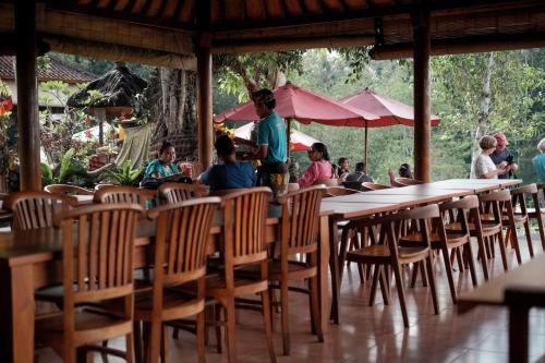 a group of people sitting at tables in a restaurant at Mahagiri Resort & Restaurant in Menanga