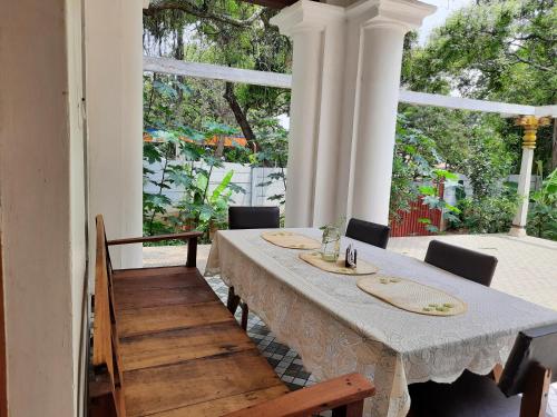 een eetkamer met een tafel en stoelen op een veranda bij Heritage Home, Hampe's in Mysore