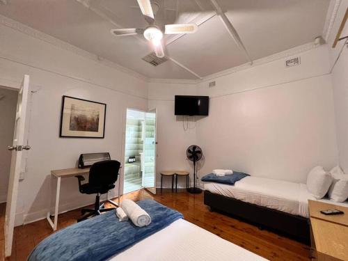 1 dormitorio con 2 camas, escritorio y ventilador de techo en Group house with views of the salt pool and spa en Mitcham