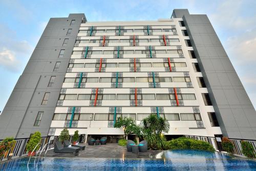 a large white building with a pool in front of it at THE 1O1 Palembang Rajawali in Palembang