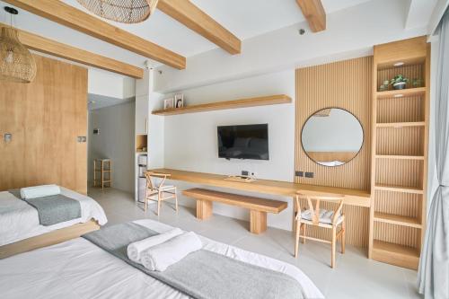 1 Schlafzimmer mit 2 Betten, einem Schreibtisch und einem Spiegel in der Unterkunft Yugen Suites 208 at Pico De Loro in Nasugbu