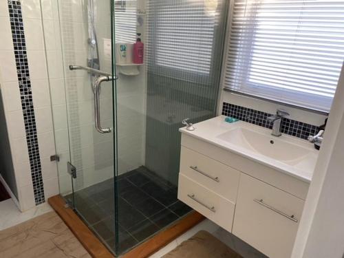 a bathroom with a glass shower and a sink at Nambucca Lodge in Nambucca Heads