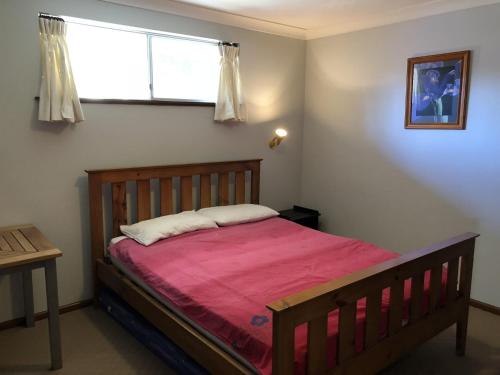 a bedroom with a wooden bed with a red blanket at Stouty's at Hat Head - No Sheets or Towels Provided in Hat Head