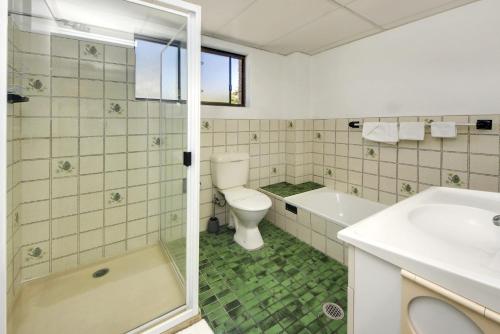 a bathroom with a toilet and a tub and a sink at Azure Beach Stop in South West Rocks