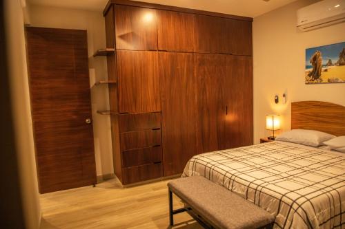 a bedroom with a bed and a large wooden cabinet at NEW Condo w/Rooftop Pool & View in Cabo San Lucas