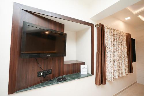 a bathroom with a flat screen tv and a mirror at Hotel Neelkiran in Navi Mumbai