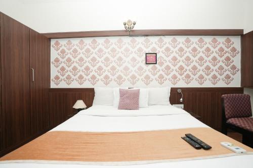 a hotel room with a bed and two remote controls at Hotel Neelkiran in Navi Mumbai