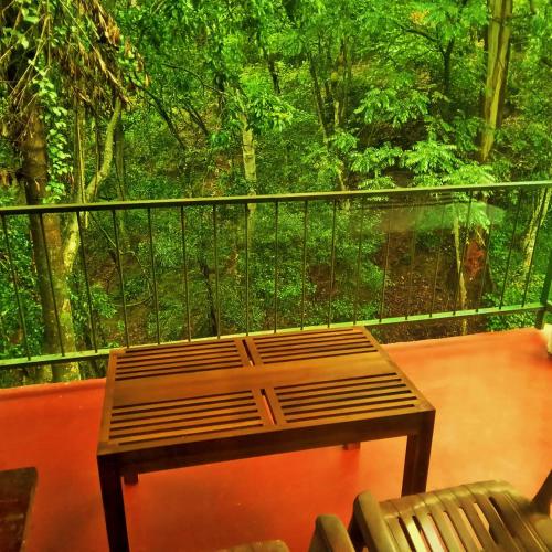 a bench on a balcony with a view of a forest at Green cottage Ella in Ella