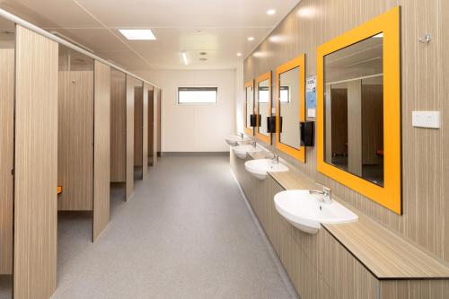 a bathroom with three sinks and a row of mirrors at BIG4 Wallaga Lake Holiday Park in Bermagui