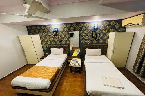 a room with three beds with lights on the wall at Hotel Neelkiran in Navi Mumbai