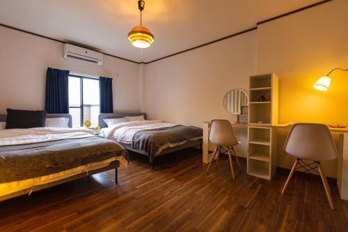 a bedroom with two beds and a desk and a table at 駐車場無料！静かな住宅街　４つの寝室でご家族でゆっくりお過ごし頂けます　7台の寝具で最大11名様まで in Osaka